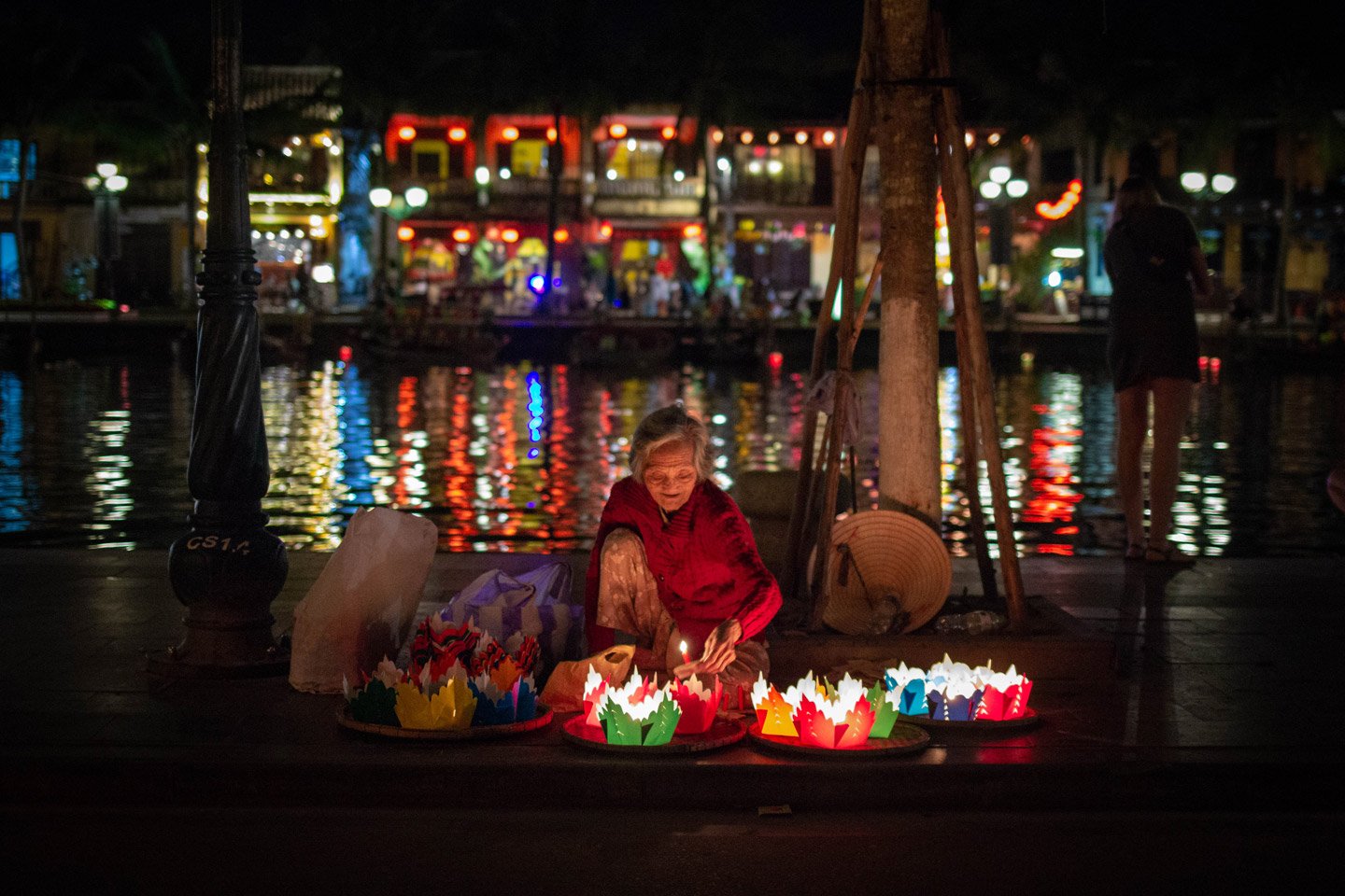 Señora encendiendo velas para arrojar al río en el pueblo de Hội An, Vietnam